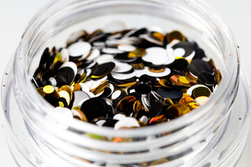 colored sequins in a plastic jar close-up
