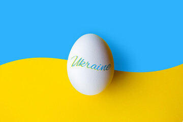 Easter egg with symbols of Ukraine. Patriotic Easter egg on the background of the flag of Ukraine. Support for Ukraine at Easter. Easter egg on a yellow background with the inscription Ukraine. War 