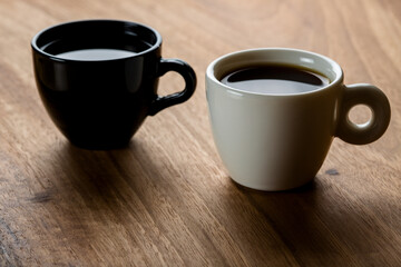 Two black and white coffee cups on wooden background