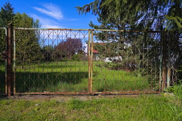 An old gate from metal, rusty rods in the countryside