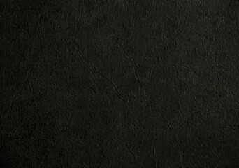 Dark background of decorative plaster with abstract spots. Unusual black or gray wall texture with beautiful patterns, creative surface background. Finishing coating for building cladding.