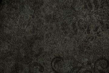 Fototapeta premium Dark background of decorative plaster with abstract spots. Unusual black or gray wall texture with beautiful patterns, creative surface background. Finishing coating for building cladding.