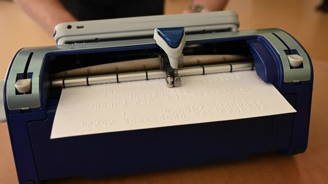 Blind man using braille typewriter. 