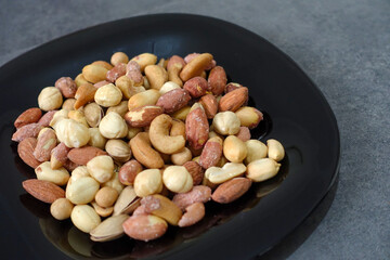 a bowl full of roasted hazelnuts, pistachios, cashews and a plate of various nuts,