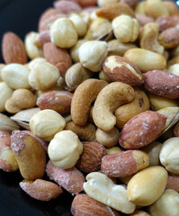 a bowl full of roasted hazelnuts, pistachios, cashews and a plate of various nuts,