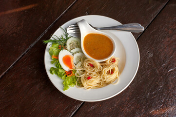 The fusion food Thai style spaghetti with  fish and coconut milk in red curry eaten with boiled egg and vegetable