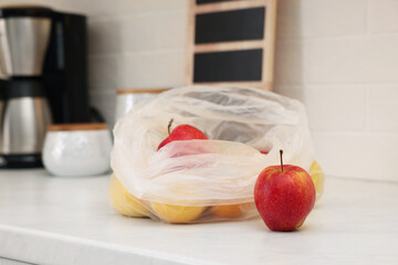 Plastic bags with different fresh products on white countertop in kitchen