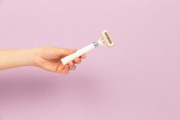 girl holding razor in hand on pink background