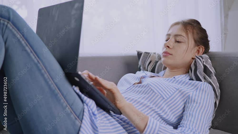 Poster female lying on sofa using computer