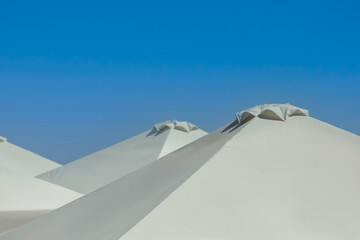 Beach umbrellas against blue sky on sunny day, closeup