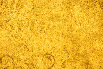 Golden wall with abstract spots as a background. Beautiful golden texture with patterns, decorative plaster. Modern bright wall painting in trendy shades, unusual spotted yellow and gold surface.