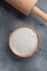 Rye flour in a wooden bowl top view on a grey concrete background