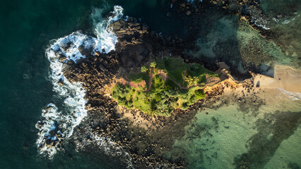 Aerial drone view of rocky shore and blue waves at Tropical paradise island. Clear blue ocean water and white splashes