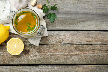 Jar of lemon sauce and ingredients on wooden table, flat lay with space for text. Delicious salad dressing