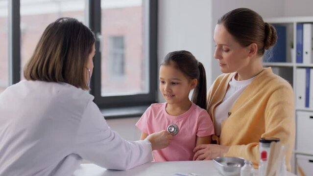 medicine, healthcare and pediatry concept - mother with little daughter and doctor with stethoscope at clinic