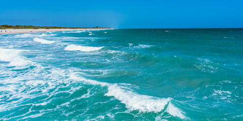 Panorama of the Atlantic Ocean in sunny windy weather. Beautiful green waves crash on a sandy beach in Florida