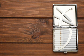 Stylish case with cigarettes on wooden table, top view. Space for text