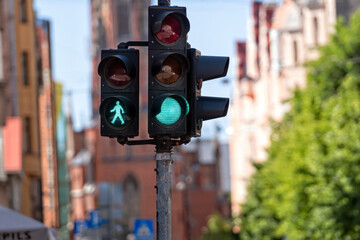 traffic semaphore with green light and green figure of pedestrian on defocused city street - obrazy, fototapety, plakaty