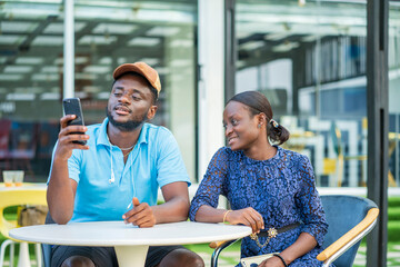 image of african guy with smart phone, black guy and lady enjoying social media- outdoor...