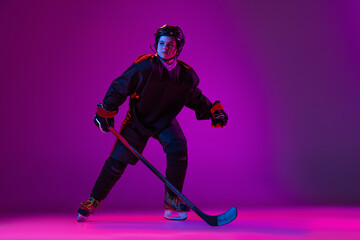 Boy, child. hockey player training isolated over purple background in neon light.