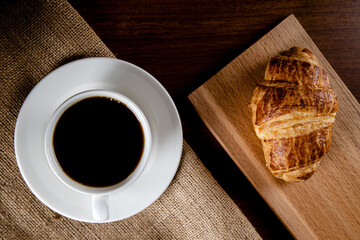 Croissant with a cup of full coffee,directly above	