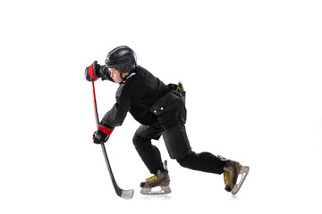 Concentration. Child, hockey player with the stick on ice court and white background.