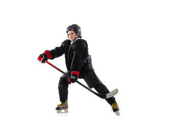 Concentration. Child, hockey player with the stick on ice court and white background.