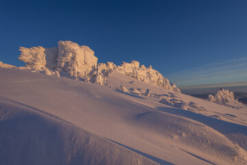 massive rocks high in the mountains after a big snowfall, beautifully covered with snow. mountain landscape with beautiful orange light from sunset with white rocks in the background. winter resort