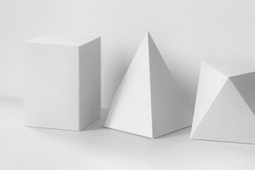 Platonic solids figures geometry. Abstract white color geometrical figures still life composition. Three-dimensional prism pyramid rectangular cube objects on gray background