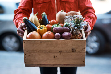 Delivered fresh right to your door. Cropped shot of a man delivering a crate full of fruit and...