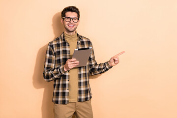 Photo of confident representative guy hold tablet point empty space device options isolated pastel color background