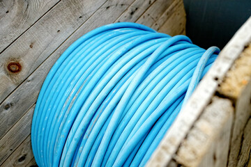 Obraz na płótnie Canvas New blue power cable is wound on wooden coil. Background. Cable for laying underground.
