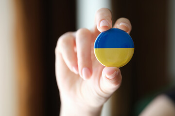 Ukraine flag badge in female hand closeup