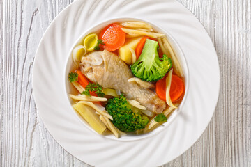 chicken vegetable soup with pasta in white bowl