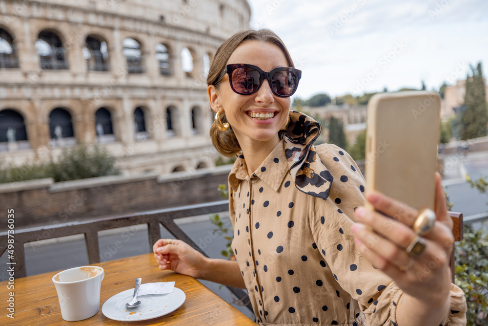 Wall mural woman having fun taking selfie with coffee at outdoor cafe on background of coliseum, the most famou