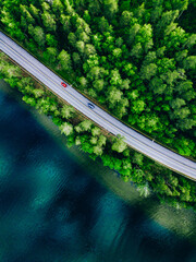 Aerial view of coastline road with green woods and blue lakes water in Finland. © NBLX