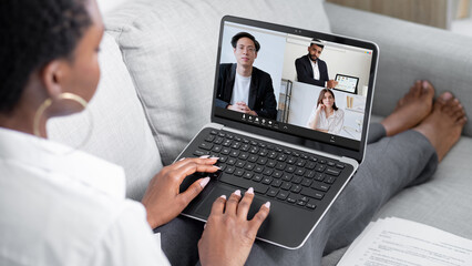 Video conference. International webcast. Internet meeting. Relaxed business woman using laptop working from home online with diverse team on screen in digital office.