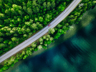 Aerial view of coastline road with green woods and blue lakes water in Finland.