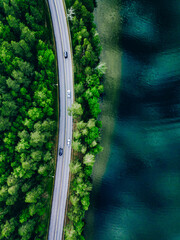 Aerial view of coastline road with green woods and blue lakes water in Finland.