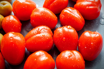 Group of wet ripe Cherry tomatoes with drops on a black plate, top view