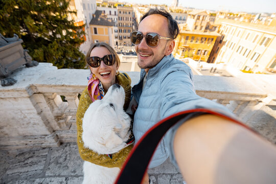 Man and woman taking selfie photo with a dog on backgorund of Rome city. Concept of happy vacations in Rome