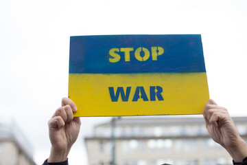 Demonstrator holding sign stop war placard. Ukraine war crisis. Anti war protests in Germany