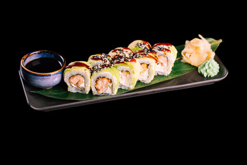Sushi set with smoked salmon, sprinkled with sesame seeds. Served with ginger, wasabi and soy sauce on dark plate with green leaf, isolated on black background. Traditional Japanese seafood. 