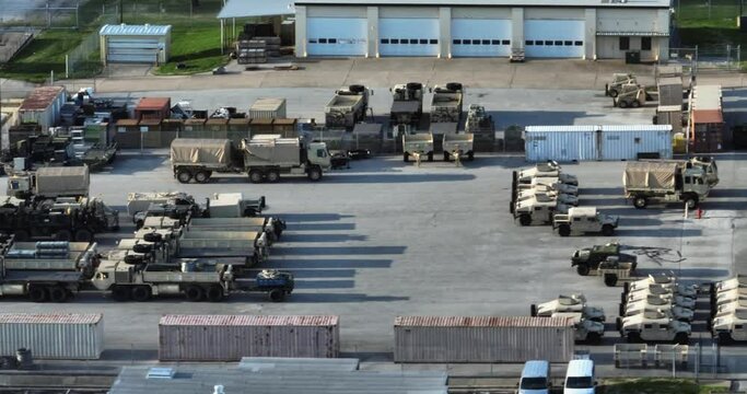 Aerial view of military vehicles and gear parked at a base - tracking, drone shot
