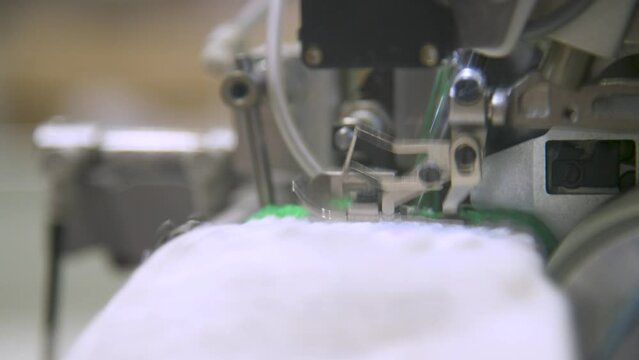 Close-up of overlock foot and cutter overlocking cuff in glove manufacturing. . The overlock machine trims the edges of the fabric. garment factory