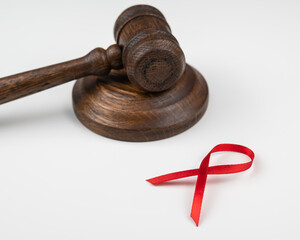 Judicial gavel and red ribbon on a white background. Symbol of the fight against AIDS.