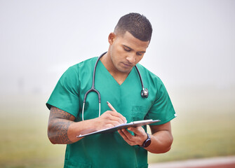 Paperwork is important. Cropped shot of a handsome young male paramedic filling out paperwork while...