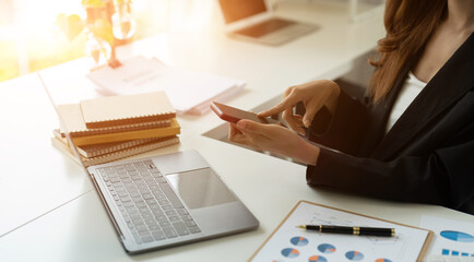 Close up hand of business accountant woman using smartphone and laptop computer for analysis financial report