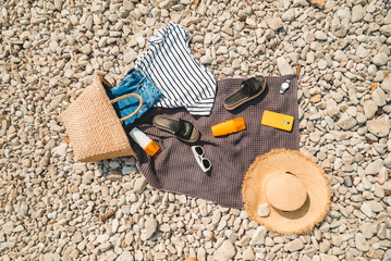 overhead view of beach stuff blanket with sun protection cream straw hat with bag