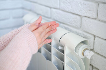 The child is hands warm their hands near the heating radiator. Saving gas in the heating season.